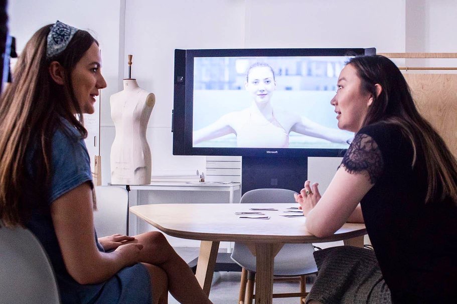 Two students discussing deep-fake technology in front to TV screen