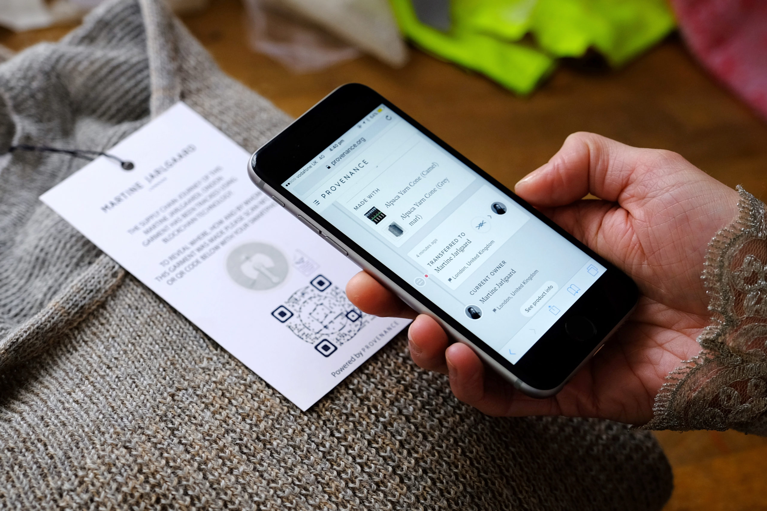 Hand hovering a phone over QR code on label of clothing, Fashion Innovation Agency